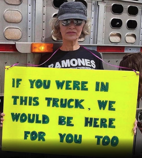 Vegan activist Regan Russell holding up a sign reading "if you were in this truck, we would be here for you too" at a pig slaughterhouse vigil