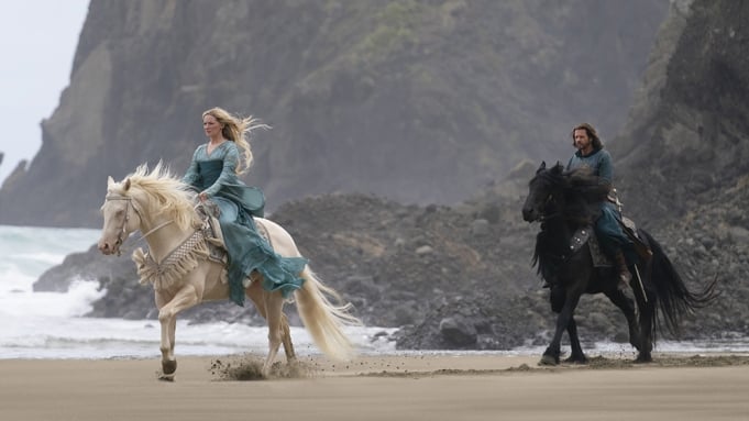 Two actors ride horses in a still of The Rings of Power, a spin-off of Lord of the Rings