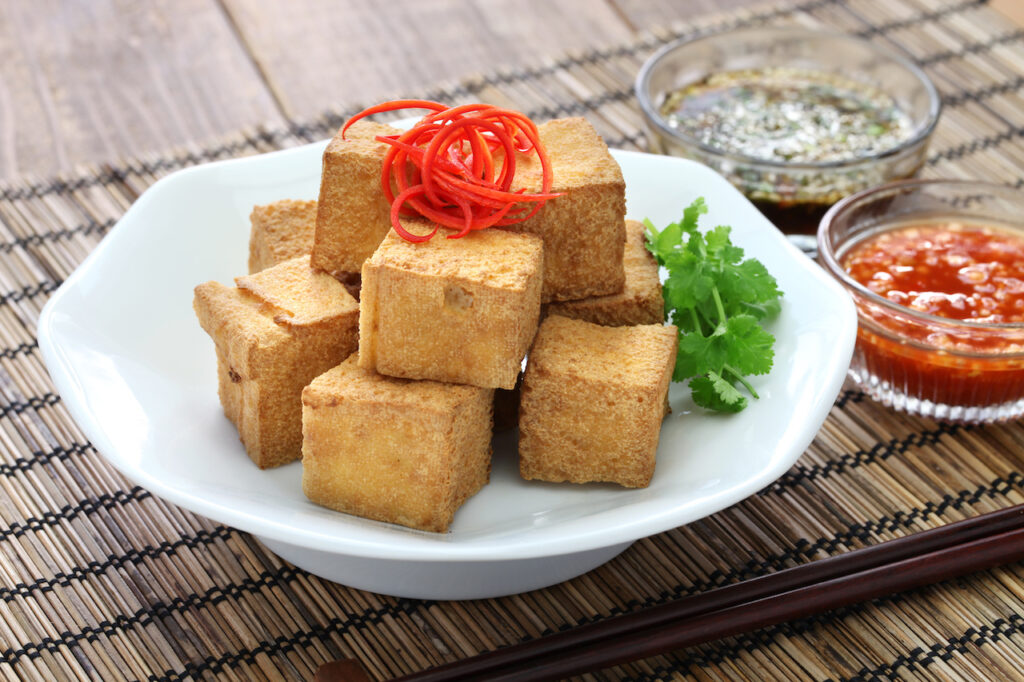 Cubes of fried tofu on a plate, served with dipping sauces