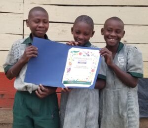 Three children from the Ugandan Atlas Community School in East Africa holding their TeachKind vegan award
