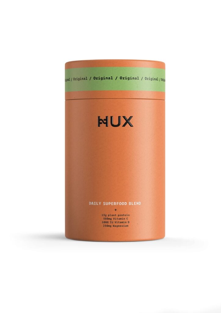 An orange tube of Hux vegan protein powder on a white backdrop