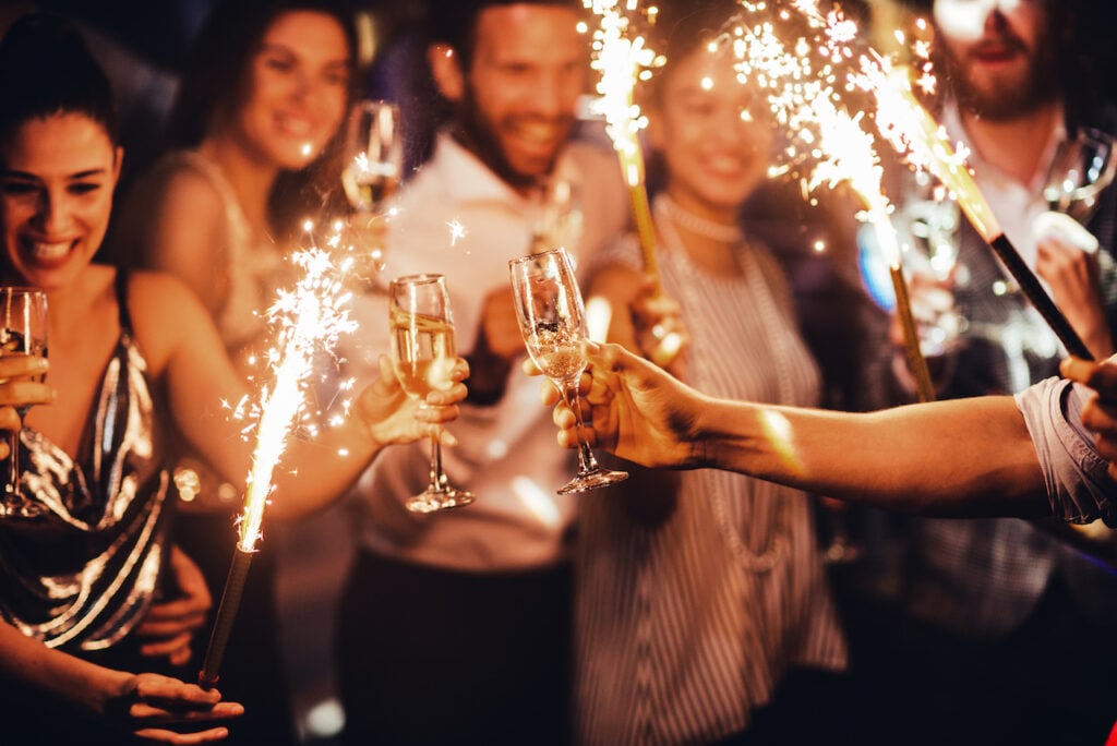 Students partying at a formal party event with sparklers and drinks in hand