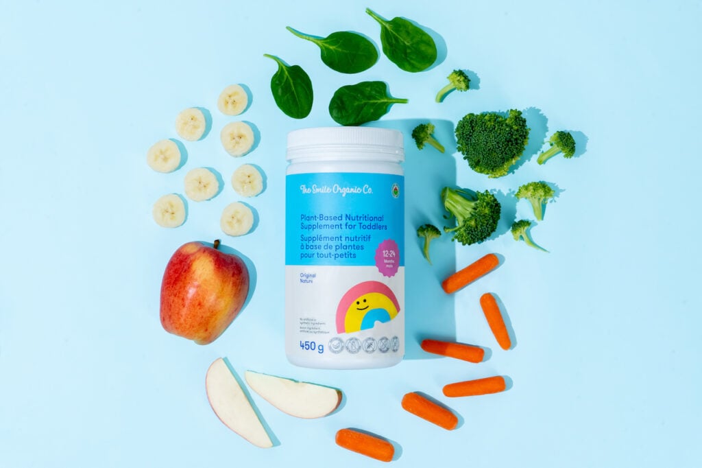 Smile organic Co's oat-based nutritional drink for toddlers surrounded by vegetables on a blue background