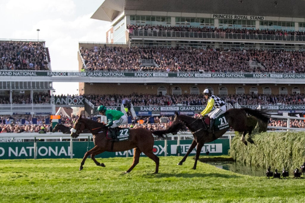 Horses racing at the Grand National while spectators watch on