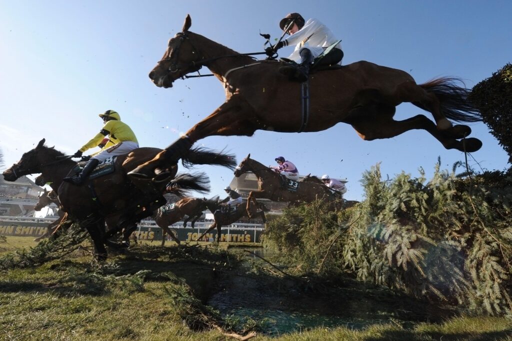 A horse jumps over a fence at the Grand National in Aintree