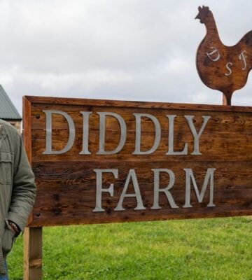 Jeremy Clarkson standing by a sign reading "Diddly Squat Farm Shop"