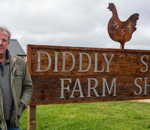 Jeremy Clarkson standing by a sign reading "Diddly Squat Farm Shop"