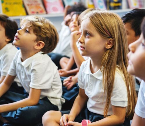 Children at a UK primary school looking concerned while sat on the classroom floor