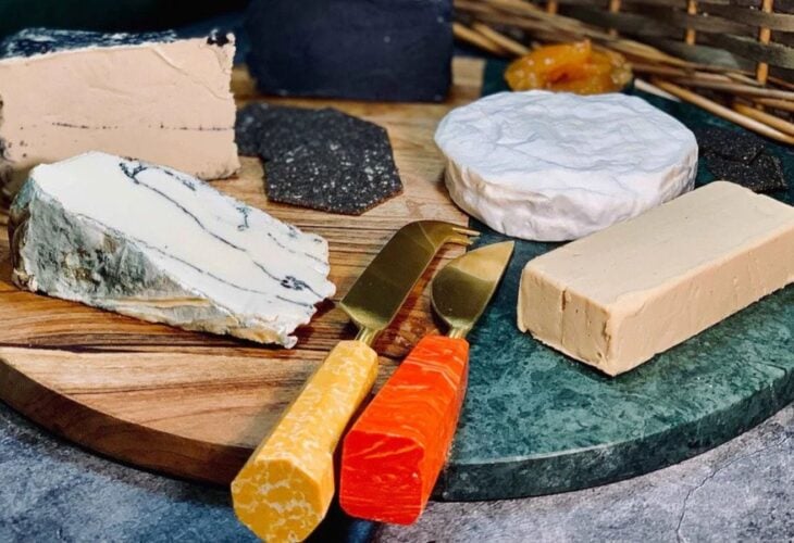 A selection of vegan dairy-free cheeses from la Fauxmagerie on a wooden and resin board with appropriate knives