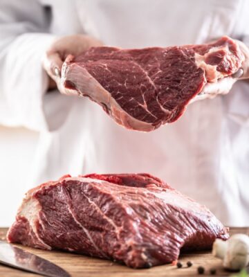 Slabs of red meat being handled by a butcher