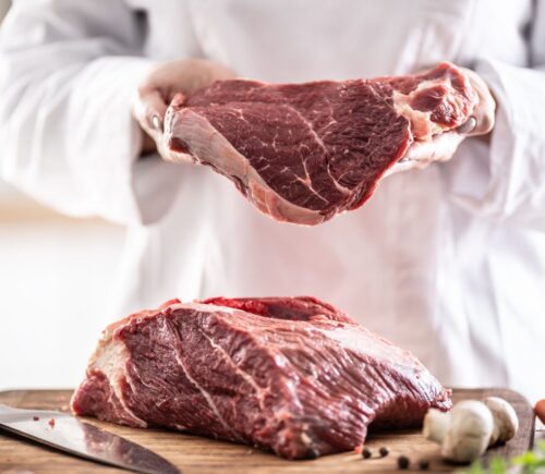 Slabs of red meat being handled by a butcher