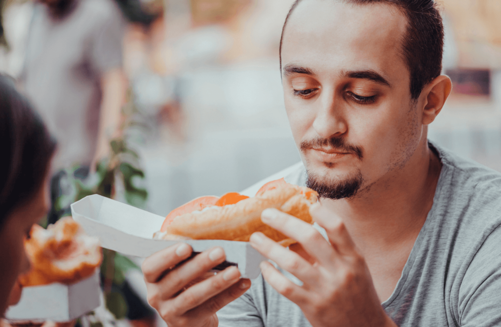 A man eating a sandwich containing meat