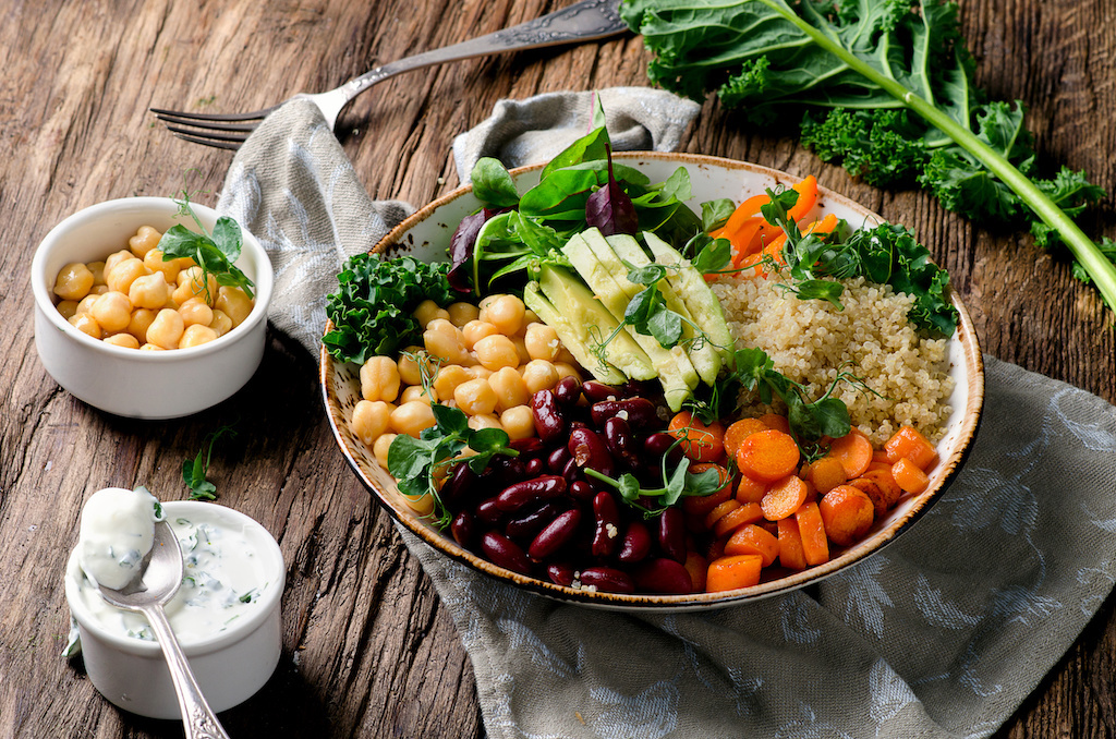 A plant-based buddha bowl with fresh produce on a wooden table