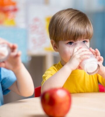 Two children drink milk and eat apples