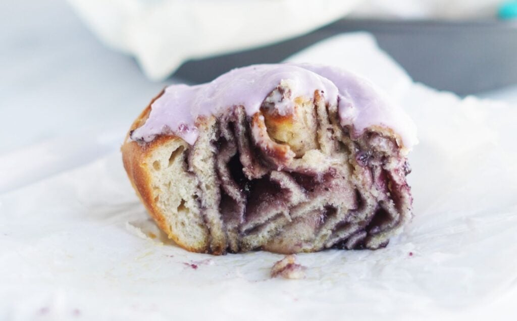 A vegan blueberry cinnamon roll from a recipe, cut in half to show all the swirls and jam inside