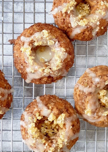 Small vegan nut-free carrot cakes with lemon drizzle and hemp heart praline cookies in a bundt tin and shot on a cooling rack