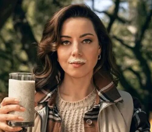 Actor Aubrey Plaza in a new satirical anti-vegan advert funded by the dairy industry, holding a glass of 'wood milk' with a milk mustache