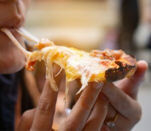 A person eating a dairy cheese pizza