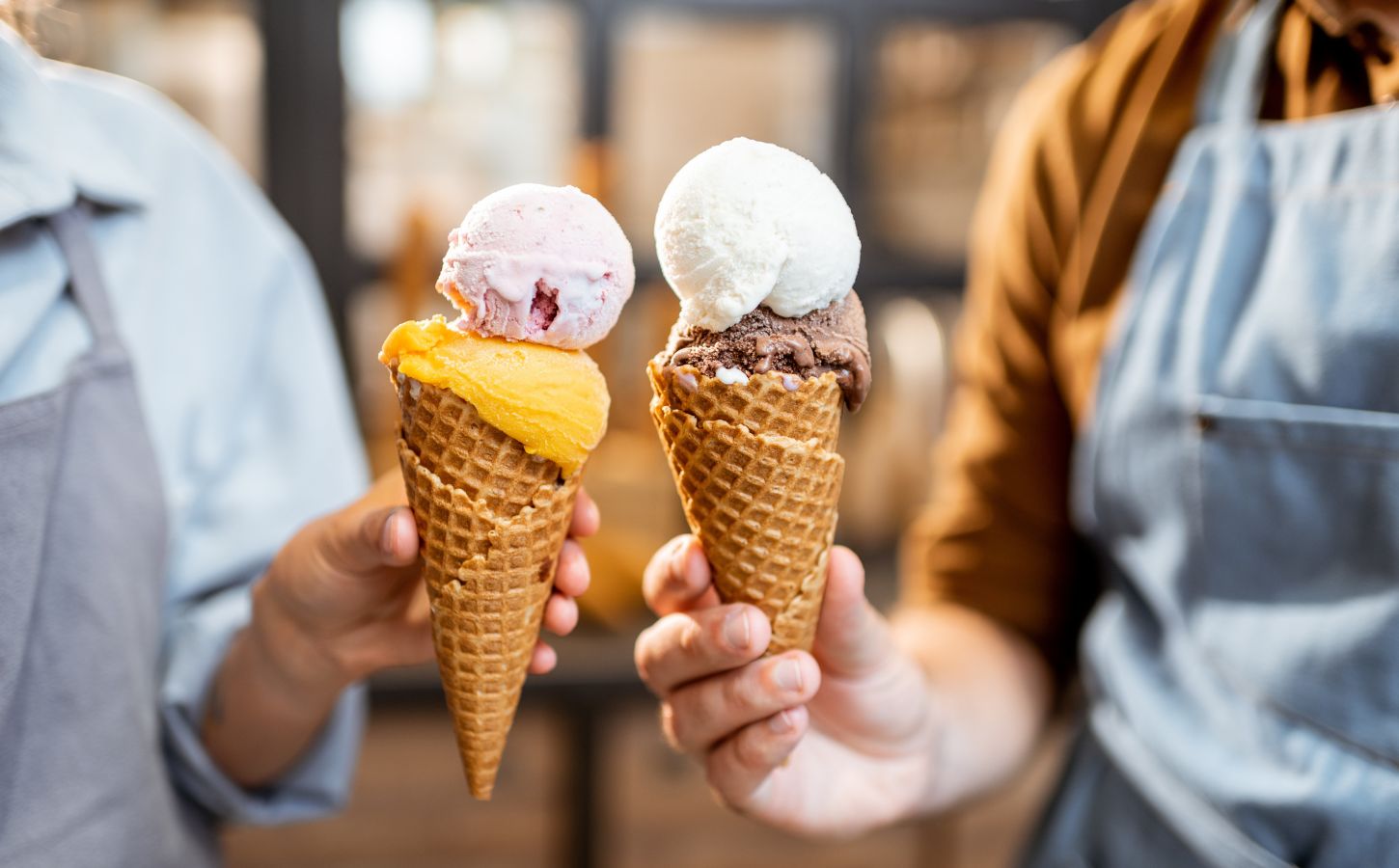 Hands holding two ice cream cones containing scoops of dairy-free ice cream