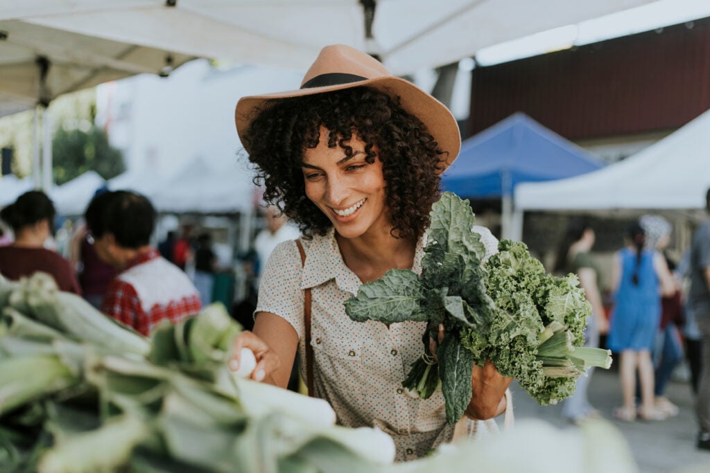 A woman buying leafy green vegetables, a good source of calcium for vegans