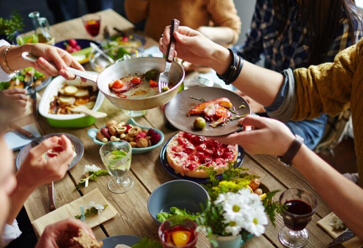 People eating meat, dairy, eggs, and plant-based food at a dinner table