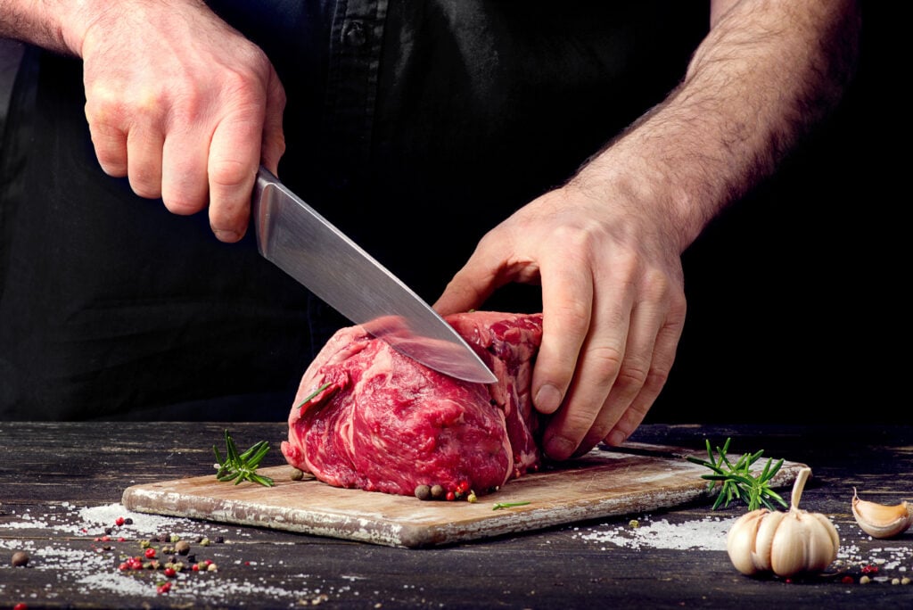 A man cutting a raw beef steak