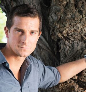 Bear Grylls, owner of an ancestral supplements brand that promotes the benefits of organ meat, resting his hand on a tree