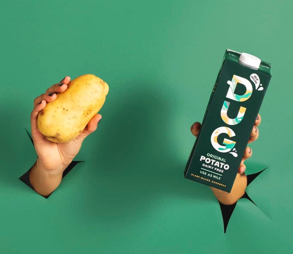 Vegan DUG potato milk next to a potato in front of a green background