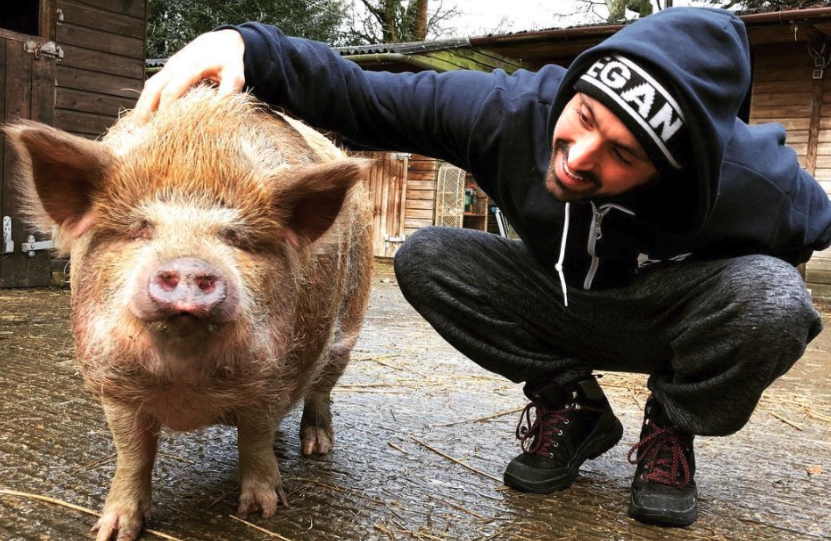 Vegan activist Joey Carbstrong next to a rescued pig