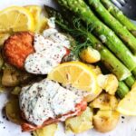 Vegan salmon fillets served with creamy dill sauce and vegetables on a white speckled plate