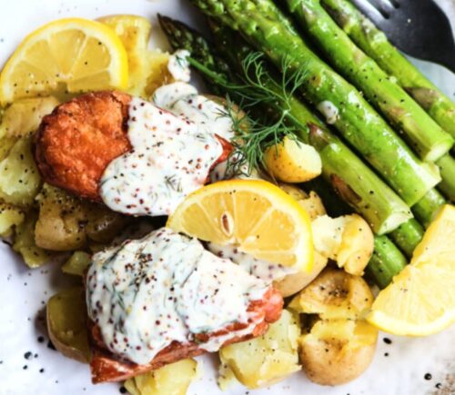 Vegan salmon fillets served with creamy dill sauce and vegetables on a white speckled plate