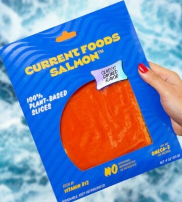 a person's hand holding a packet of vegan salmon made by plant-based seafood brand Current Foods