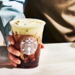 A Starbucks drink containing vegan milk in the hand of a barista
