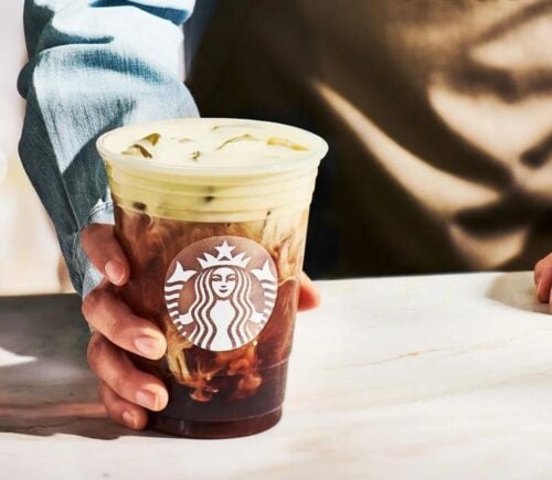 A Starbucks drink containing vegan milk in the hand of a barista