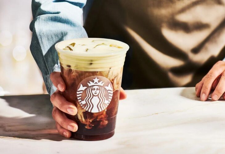 A Starbucks drink containing vegan milk in the hand of a barista