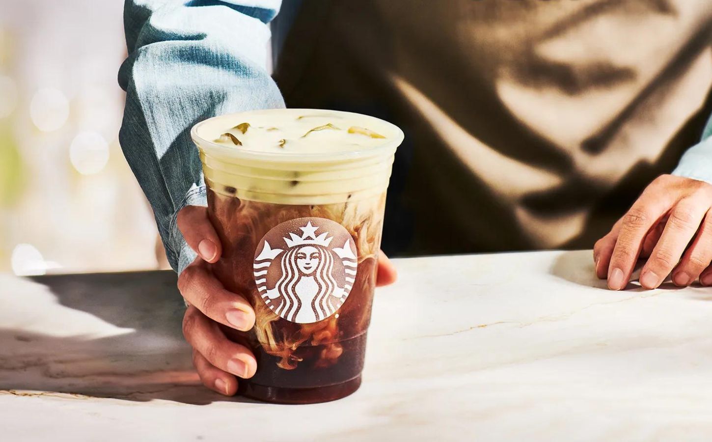 A Starbucks drink containing vegan milk in the hand of a barista