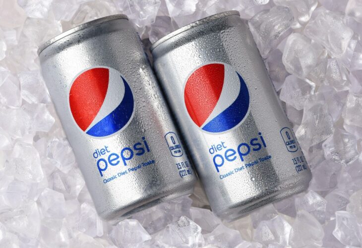 Two cans of non-vegan soft drink Diet Pepsi lying on a bed of ice