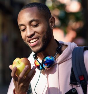A man walking while eating an apple