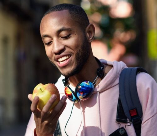 A man walking while eating an apple