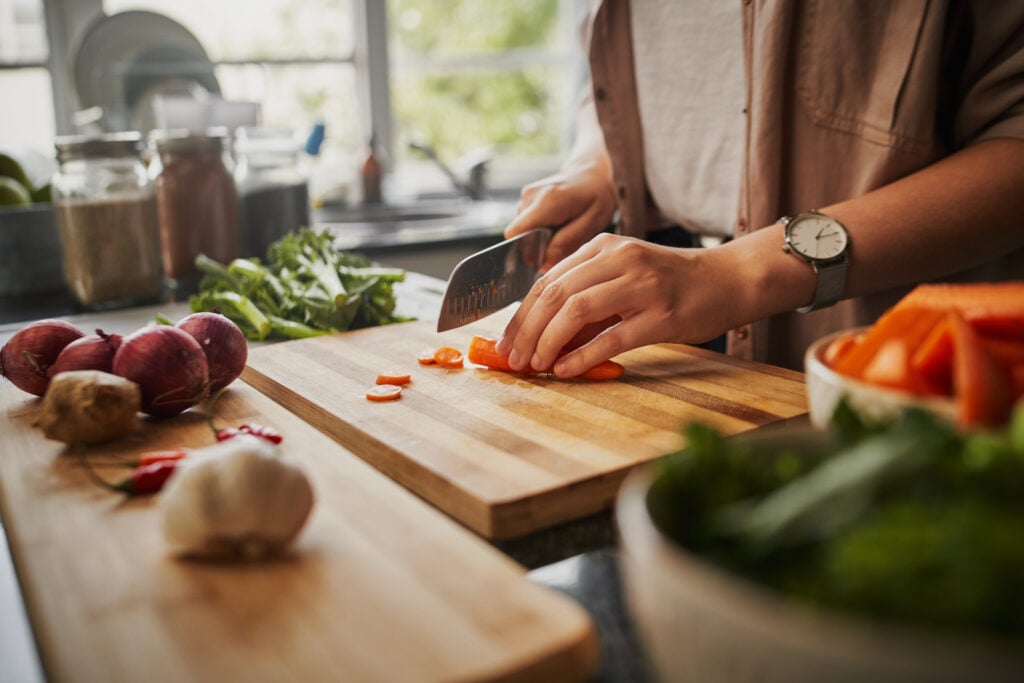 A person cutting carrots on a chopping board