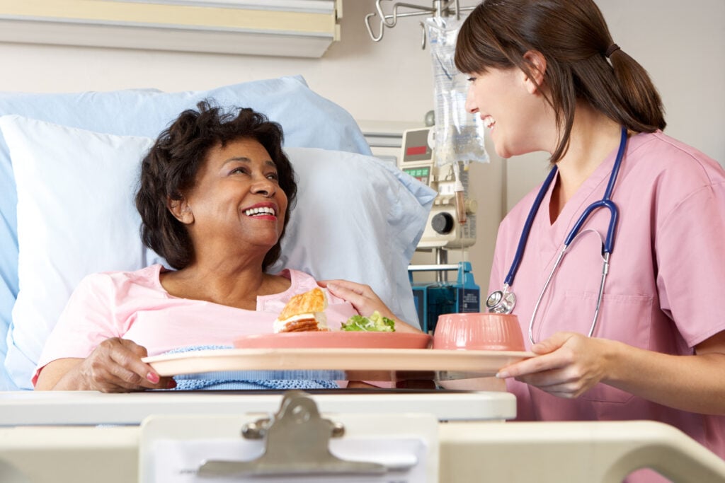 A woman being served vegan food in a hospital bed