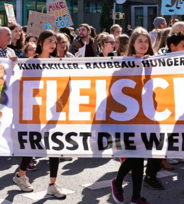 German climate protestors holding a sign saying "meat eats the world" in German