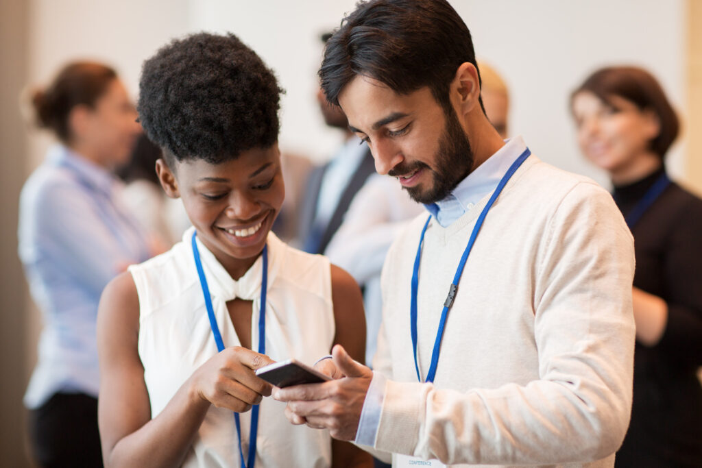 two summit attendees smiling and looking at a phone