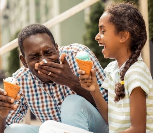 A dad and daughter enjoying vegan ice cream in the sun