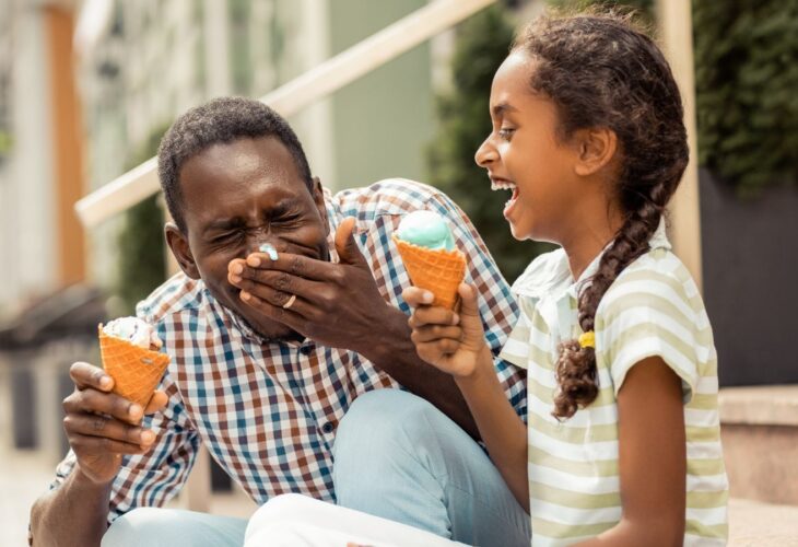 A dad and daughter enjoying vegan ice cream in the sun