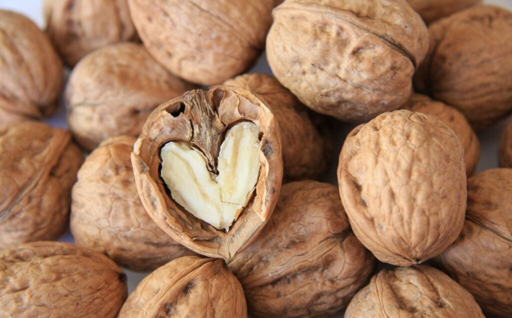 A pile of walnuts, a vegan source of omega-3, including on in the shape of a heart