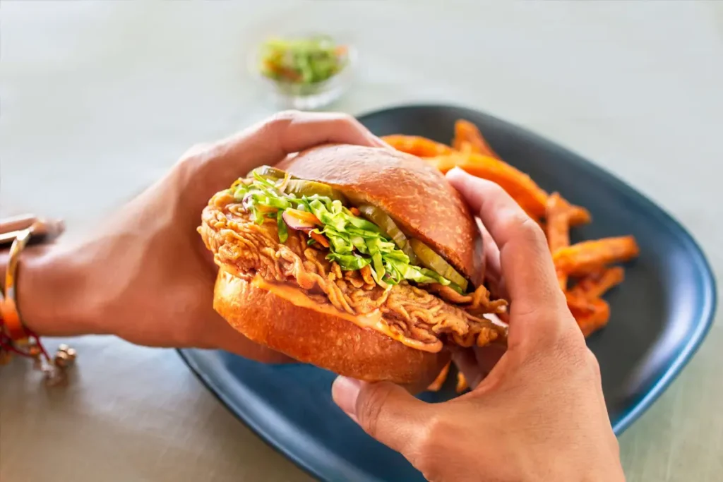 Hands holding a burger containing UPSIDE Foods' cell-based chicken