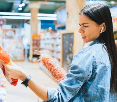 A person looking disgruntled by a vegan label on food while out shopping
