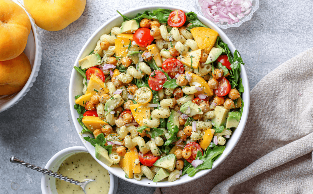 Vegan Arugula and tomato Pasta Salad featuring peach and other plant-based ingredients