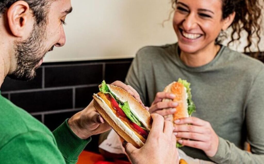 Two friends eating a Burger King vegan burger off the plant-based menu